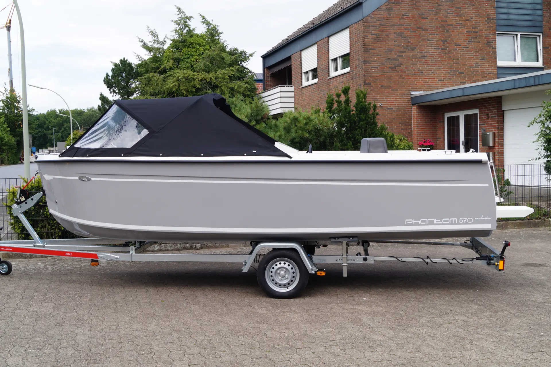 Phantom 570 Exclusive Seitenansicht – Motorboot mit schwarzem Verdeck auf Trailer