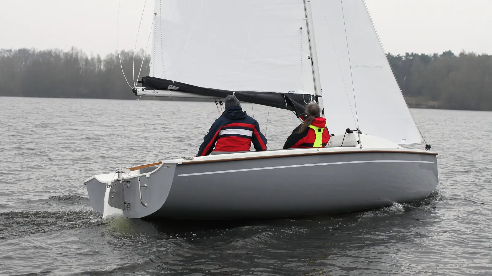 Neptun 220 DC Segelboot in Heckansicht mit zwei Personen im Cockpit unter Segel